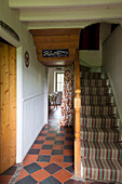 Gestreifter Treppenteppich mit terrakottafarbenem Fliesenflur in einem Ferienhaus in Ceredigion, Wales, UK