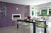 Candles in iris patterned alcoves of purple dining room with sat table and window seat in Berkshire home, England, UK