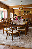 Glass chandelier above wooden dining table with glassware in London home, UK