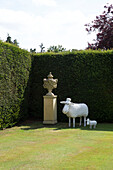 Zeitgenössische Schafsstatuen mit historischem Sockel in einer Ecke eines Gartens in London, England, UK