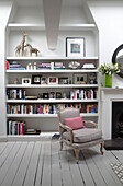 Grauer Sessel mit rosa Kissen und Regal in Londoner Stadthaus England UK