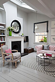 Black circular mirror above fireplace with armchair in living room of Georgian London townhouse England UK