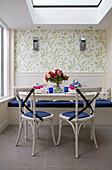 Schnittblumen auf einem Küchentisch mit blauen Stühlen in einem Stadthaus in London, England, Vereinigtes Königreich