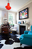 Türkisfarbener Sessel mit Tierfellteppich und hölzernem Schreibtisch und Stuhl im Arbeitszimmer eines Stadthauses in London, England, Vereinigtes Königreich
