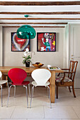 Red and white chairs at wooden dining table with colourful modern artwork in London townhouse, England, UK