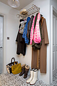 Mäntel und Schals mit Stiefeln und Taschen auf einem Regal im Flur eines Londoner Hauses, England, UK