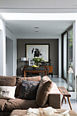 Dining table and artwork with brown sofa in contemporary Sussex home, England, UK