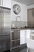 Silberne Uhr über einer Aluminium-Einbauküche mit Schlauchhahn in einem modernen Haus in Sussex, England, UK