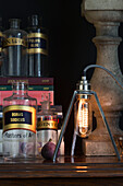 Moderne Leuchte mit alten Medizinflaschen und Feige auf einem hölzernen Beistelltisch in Sussex, Großbritannien