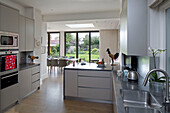Offene Einbauküche und Esszimmer mit Blick durch Terrassentüren in den Garten eines Hauses in Großbritannien