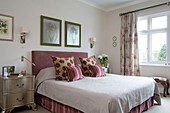 Patterned cushions with upholstered headboard on double bed with gold metallic bedside cabinet in UK home
