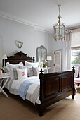 Dark wood antique bed with cushions in and coir matting in Hertfordshire home,  England,  UK