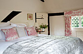 Toile de jouy-Vorhang und Kissenstoff in einem Fachwerkschlafzimmer in einem britischen Bauernhaus