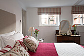 Gestreifte Raffrollos am Fenster mit Schminktisch und bestickten Kissen in einem Londoner Schlafzimmer, England, UK