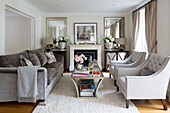 Grey sofa with pair of buttoned armchairs in classic living room of London home   England   UK