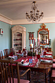 Chandelier above polished wooden dining table in Sussex home  England  UK