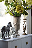 Ornaments and cut flowers on side cabinet in Berkshire home,  England,  UK