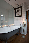 Lit tealights with silver candelabra and antler in picture frame with grey freestanding bath Surrey home   England   UK