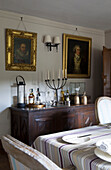 Gilt-framed oil paintings above wooden sideboard in Sussex dining room   England   UK