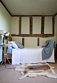 Einzelbett mit Pelzteppich in einem Fachwerkhaus in Sussex England UK