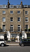 Cars parked in street with brick exterior of 5-storey London townhouse   England   UK