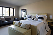 Black racing striped cushions on double bed with leather sofa at window in London home,  England,  UK