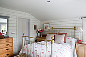 Brass bed in sunlit bedroom of Surrey home, England, UK