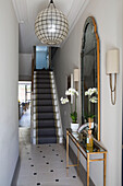 Vintage mirror and lampshade in tile hallway of London home with grey carpeted staircase, England, UK