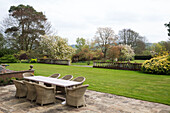 Cane furniture at table on terrace in grounds of Pewsey country house Wiltshire England UK 