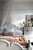 Net canopy above wooden bed with quilted fabrics in Norfolk home England UK