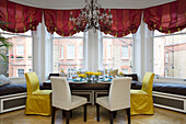 Gold and cream dining chairs at table with window seat in London townhouse UK