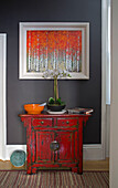 Modern artwork above Chinese cabinet with orchid in London townhouse UK