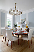 White leather chairs at table in light blue panelled Georgian dining room of London townhouse England UK