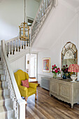 Yellow armchair in staircase hallway of Sussex country house England UK