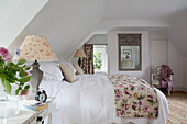 Pair of lamps at bed with floral bed cover in Sussex country house England UK