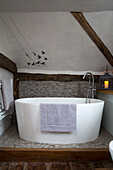 Freistehende Badewanne mit Vogel-Mobile im Dachgeschoss eines Cottage in Surrey, England