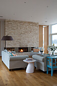 Light grey sofas with side table and exposed stone wall in Lechlade home Gloucestershire England UK