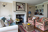 Equestrian artwork above fireplace with pair of matching armchairs and book shelves in Georgian home Berkshire England UK