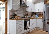 White fitted kitchen with silver upright fridge in London home England UK