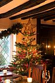 Weihnachtsbaum am bleiverglasten Fenster im Esszimmer eines Hauses in Kent, England UK