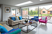Pink and blue armchairs with sofa and coffee table below skylights in modernised Victorian Sussex cottage England UK
