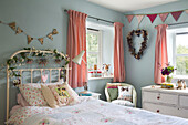 Gingham curtains with bunting and floral garlands in girls bedroom in 19th century Somerset cottage England UK