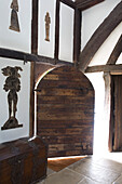 Gewölbte Holztür mit Figuren und Holztruhe in einem Fachwerkbauernhaus in Kent, Großbritannien
