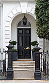 Classic black front door and gateposts at exterior of London townhouse UK