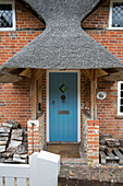 Reetgedeckter Eingangsbereich mit Brennholz an einem unter Denkmalschutz stehenden Cottage (Grade II) Hampshire England UK