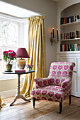 Rosa gepolsterter Sessel und Beistelltisch mit Sockel im Erker eines Hauses in Sussex, England UK