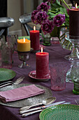 Lila und grünes Gedeck mit brennenden Kerzen auf dem Esstisch in Sussex, England UK