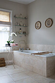 Orchidee neben der Badewanne mit Vintage-Wandregal in einem Badezimmer in Sussex, England UK