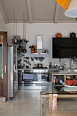 Black wall mounted storage unit in stainless steel kitchen with glass-topped table in Ithaca villa Greece