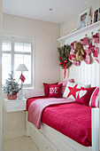 Red cushioned daybed with Christmas stockings in London family home England UK